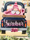 A decorative wooden sign shaped like the back of a dark blue pickup truck carrying a pink-and-white gnome, pink hearts, and pink awareness ribbons. The front panel reads “Survivor” in pink script, and a smaller sign says “fight.