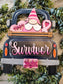 A decorative wooden sign shaped like the back of a pickup truck, featuring a pink and white gnome, pink hearts, a pink ribbon, and the words 'Hope', 'Survivor', and 'fight' in layered wood pieces. The sign is photographed on a light wood surface surrounded by green eucalyptus leaves.